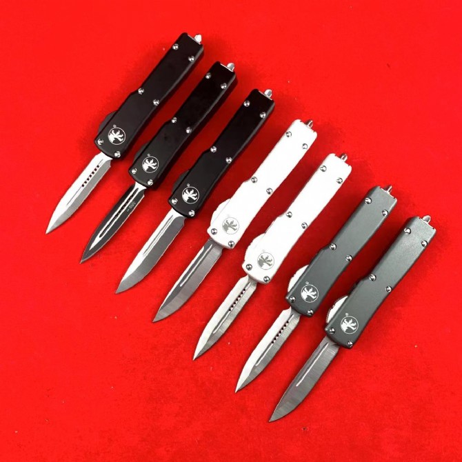Front view of seven Microtech Mini UTX-85 OTF automatic knives with multiple blade styles