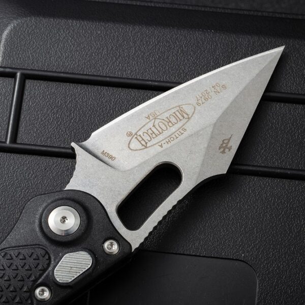 Blade close-up of Microtech Stitch automatic side-opening knife showing edge profile and finish